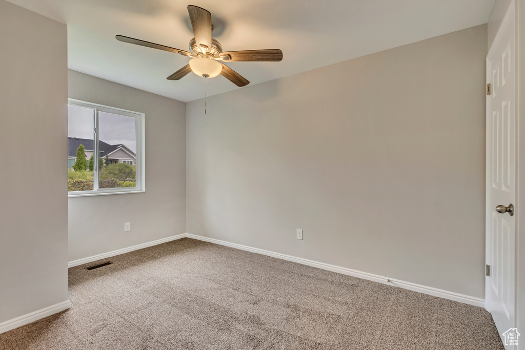 Empty room with carpet floors, ceiling fan, visible vents, and baseboards