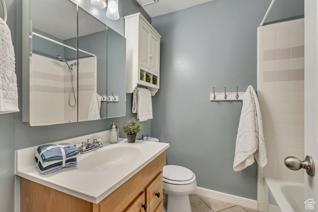 Bathroom with vanity, toilet, tile patterned floors, baseboards, and shower / washtub combination
