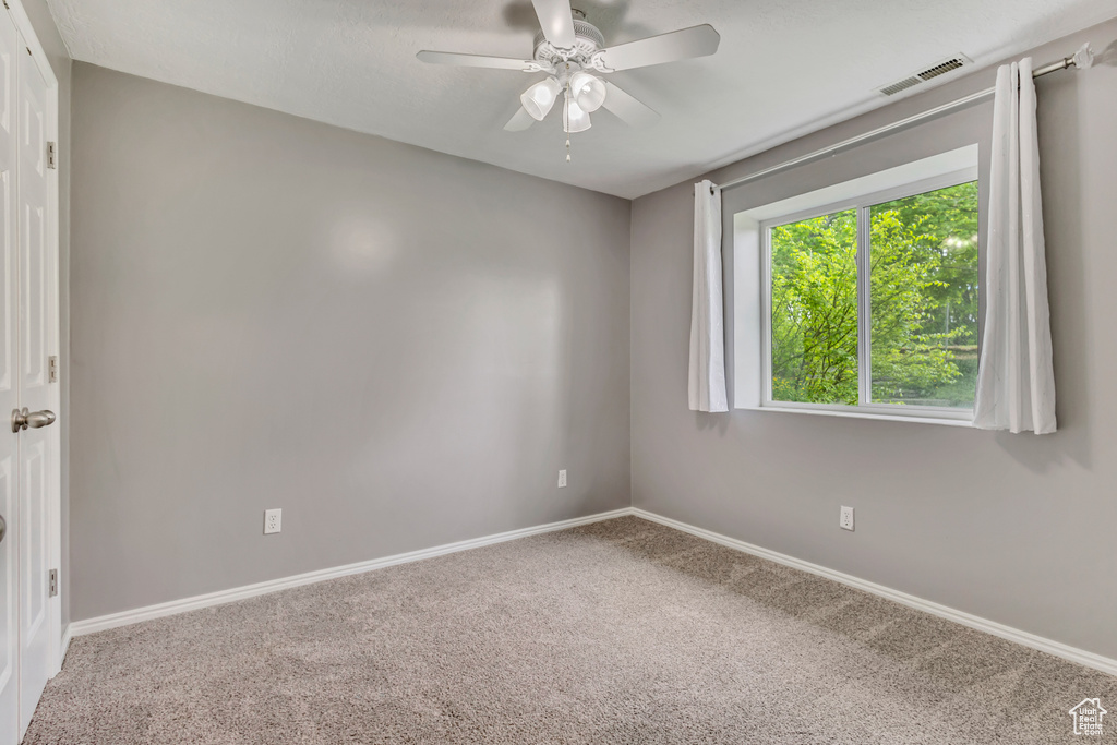 Spare room featuring baseboards, carpet, a ceiling fan, and visible vents