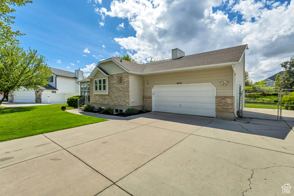 Ranch-style home with fence, an attached garage, brick siding, a front yard, and driveway
