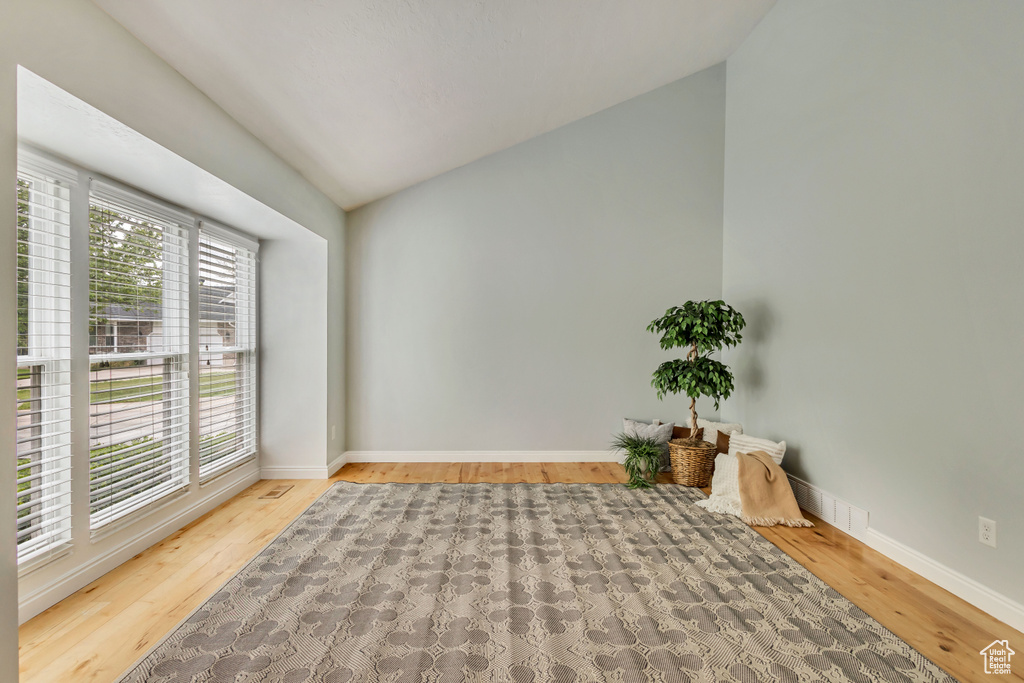 Unfurnished room with baseboards, vaulted ceiling, and wood finished floors
