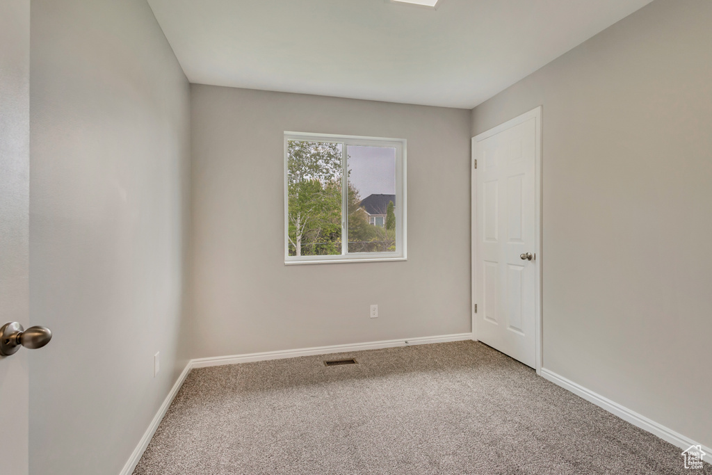 Unfurnished room featuring carpet floors, baseboards, and visible vents
