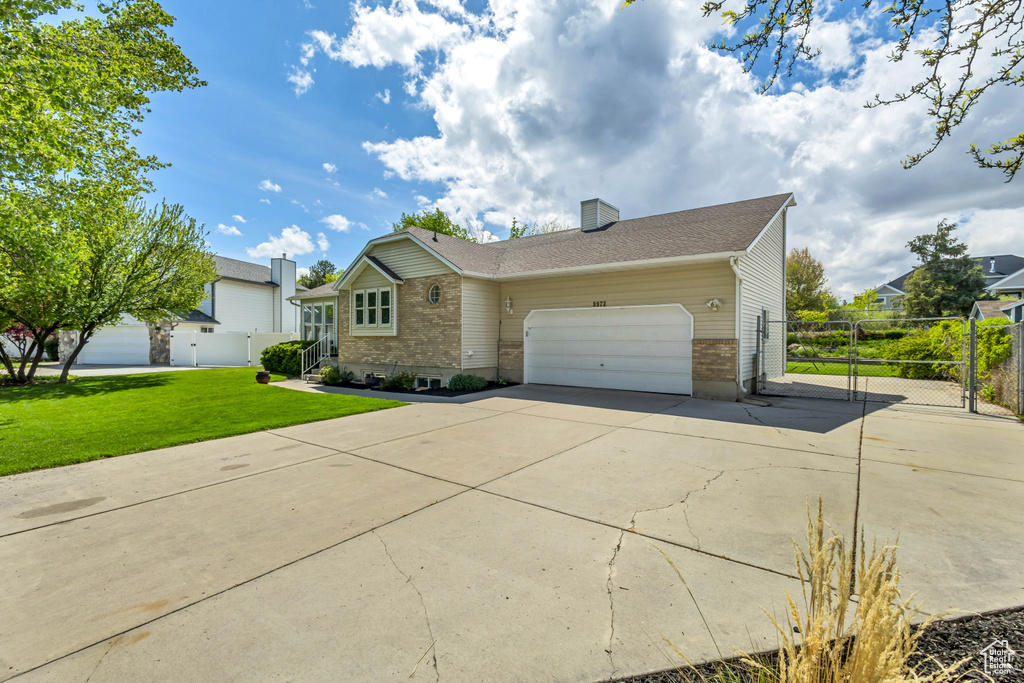 Ranch-style house with a garage, a front lawn, fence, a chimney, and concrete driveway
