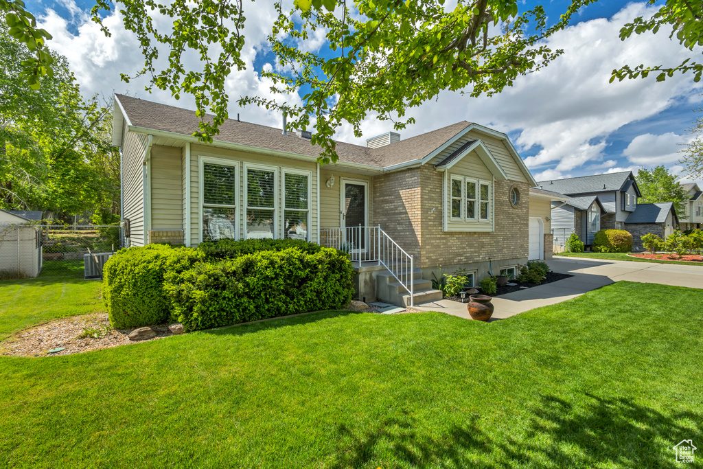 Ranch-style home featuring driveway, a front yard, a garage, brick siding, and fence