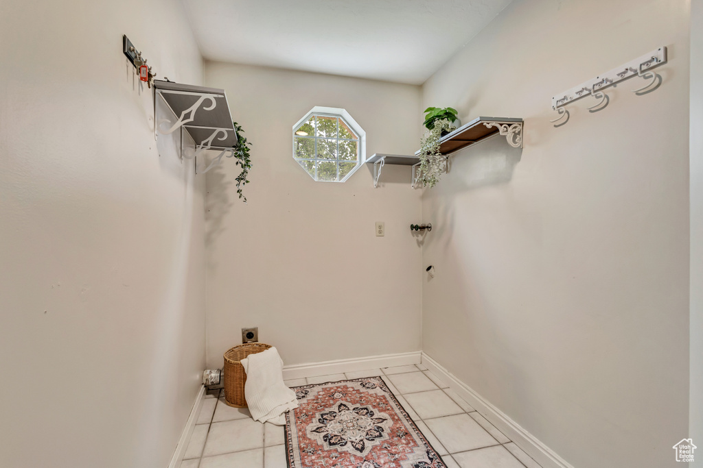 Clothes washing area featuring laundry area, baseboards, light tile patterned floors, and electric dryer hookup