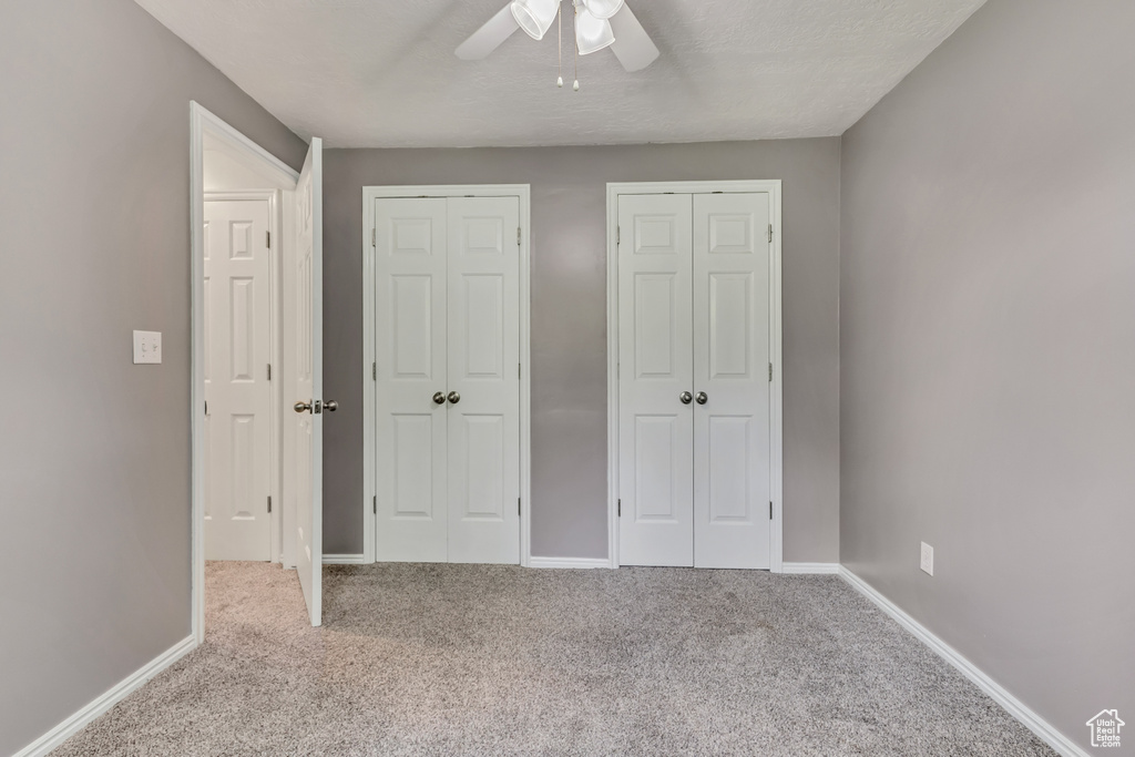 Unfurnished bedroom with carpet floors, baseboards, a ceiling fan, and two closets