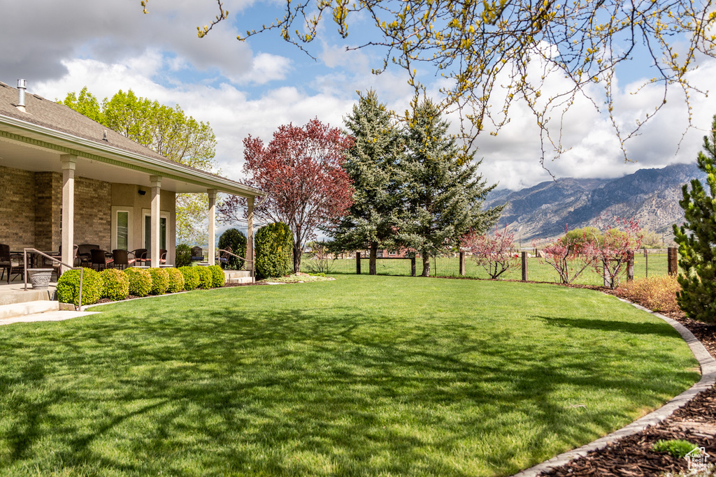 View of yard featuring fence, a mountain view, and a patio