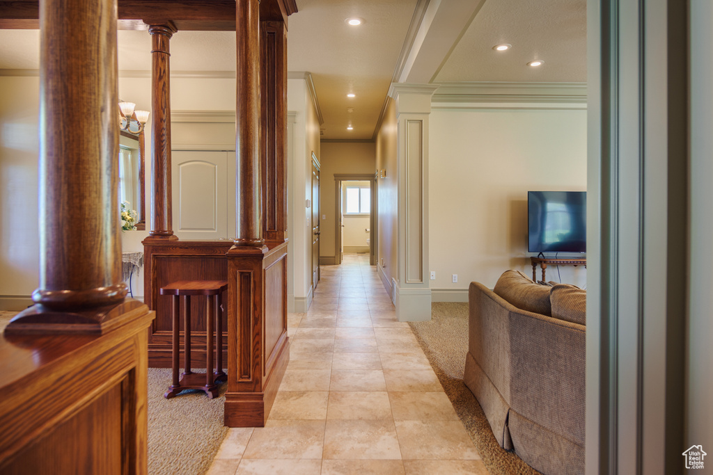 Corridor with ornate columns, recessed lighting, crown molding, and light colored carpet