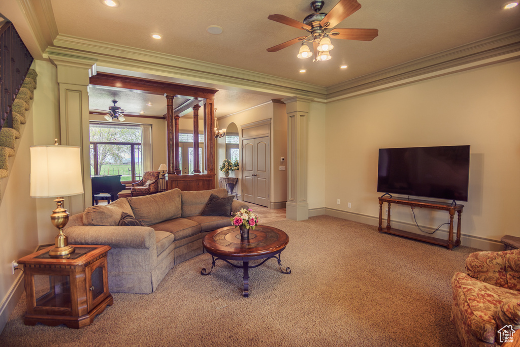 Living area featuring crown molding, baseboards, a ceiling fan, and ornate columns