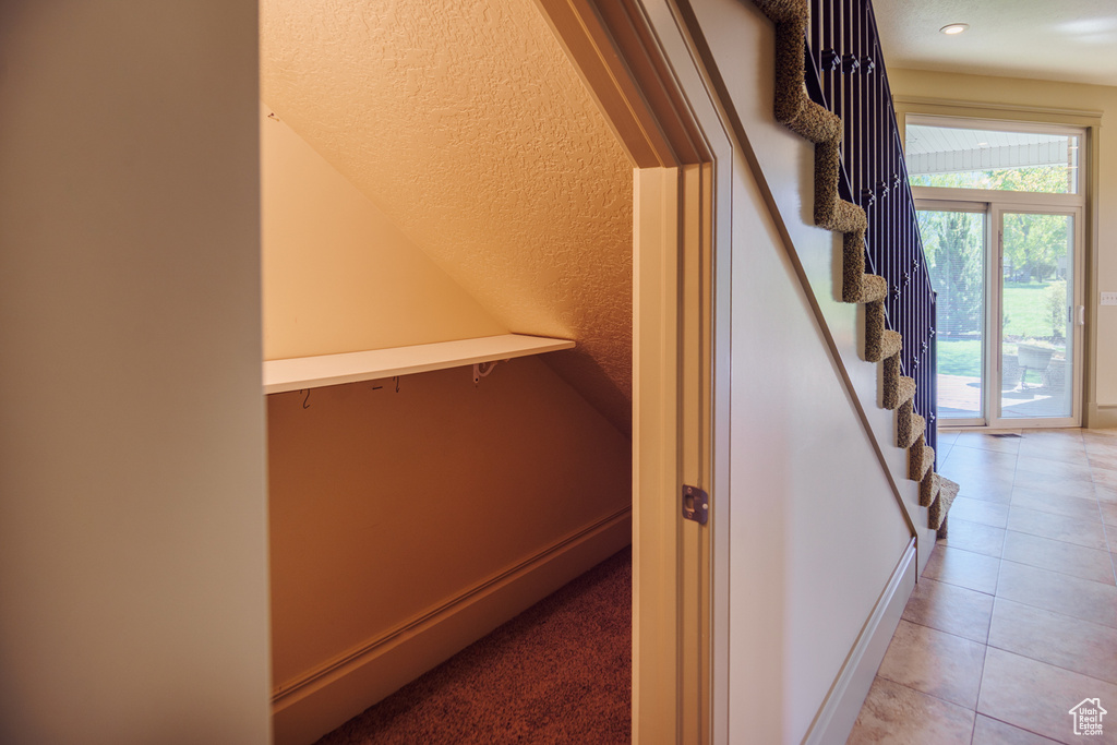 Stairs with tile patterned floors and recessed lighting