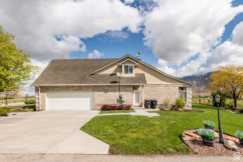 View of front of home with roof with shingles, an attached garage, driveway, and a front yard