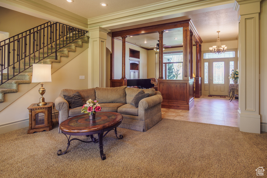 Living room featuring stairway, carpet floors, ornamental molding, and ornate columns