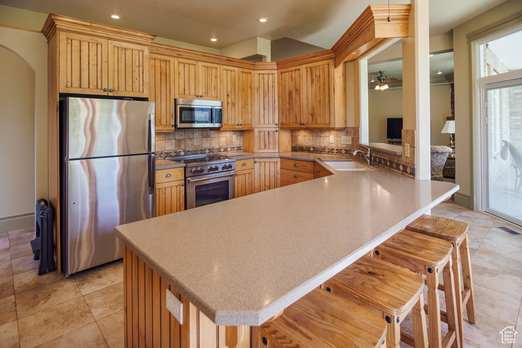 Kitchen with a sink, stainless steel appliances, recessed lighting, a peninsula, and decorative backsplash