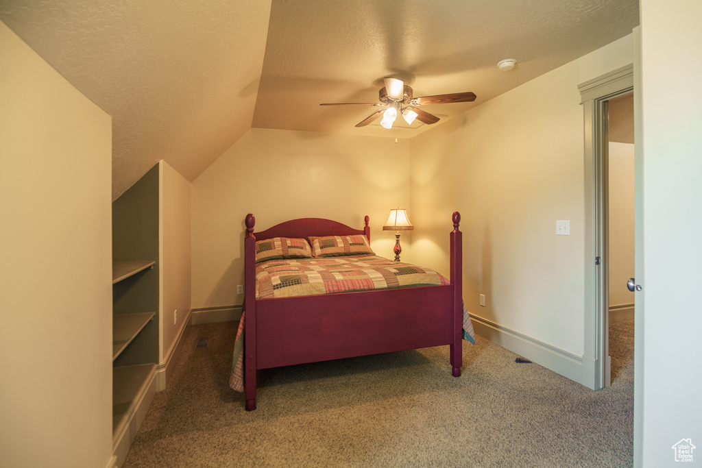 Bedroom with carpet floors, a ceiling fan, a textured ceiling, and lofted ceiling