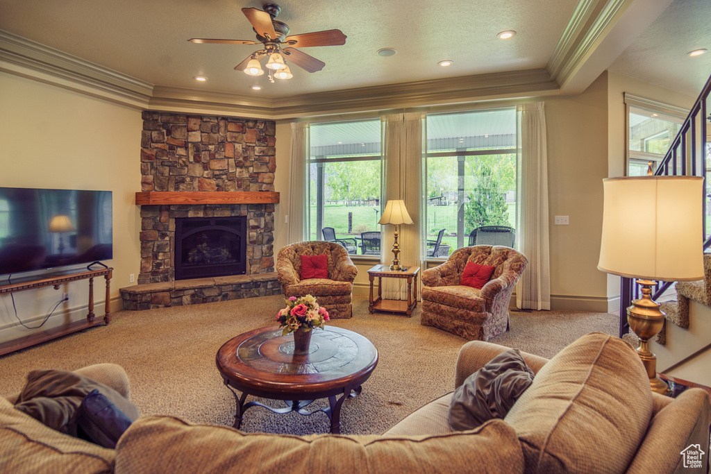 Living room with a fireplace, ornamental molding, carpet, and a ceiling fan
