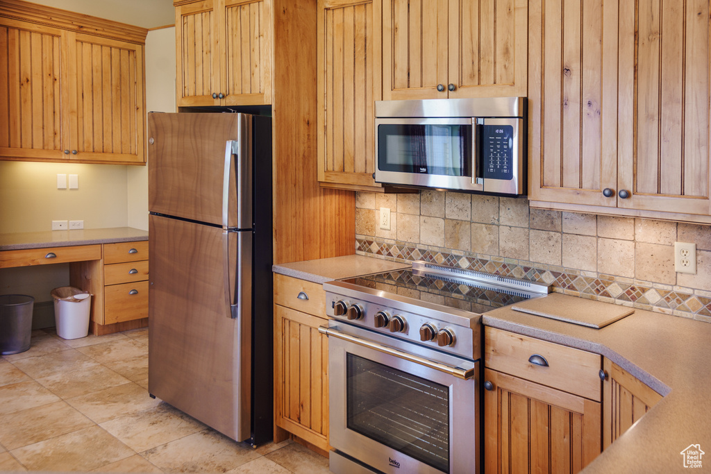 Kitchen with light countertops, appliances with stainless steel finishes, and tasteful backsplash