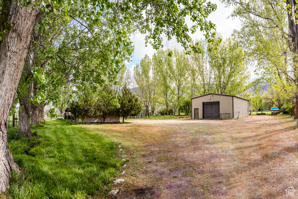View of yard featuring a detached garage, driveway, and an outbuilding