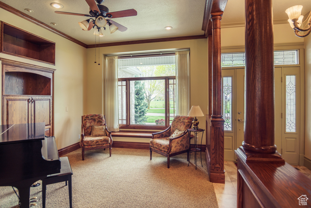 Sitting room featuring ceiling fan, light colored carpet, baseboards, decorative columns, and ornamental molding