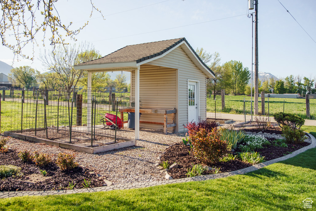 View of outbuilding featuring fence, an outdoor structure, and a vegetable garden