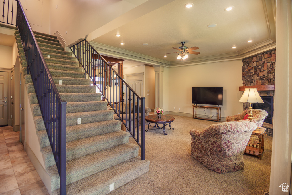 Living area with crown molding, ornate columns, a ceiling fan, and stairs
