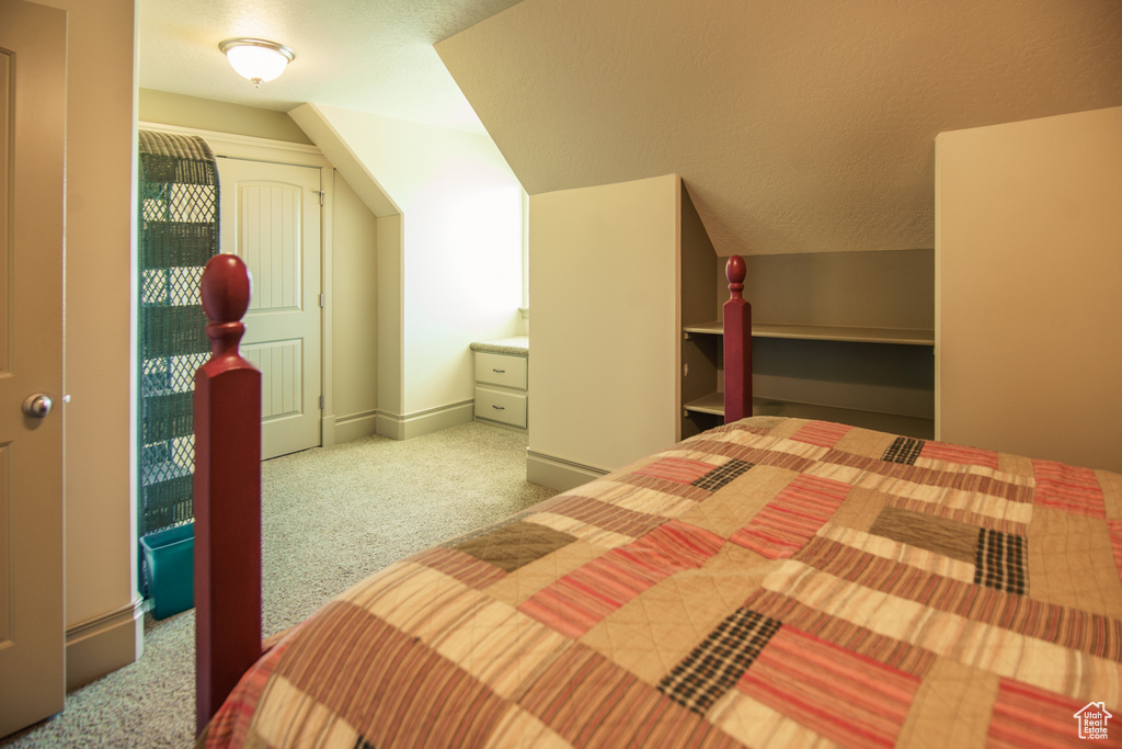 Carpeted bedroom featuring a textured ceiling and vaulted ceiling