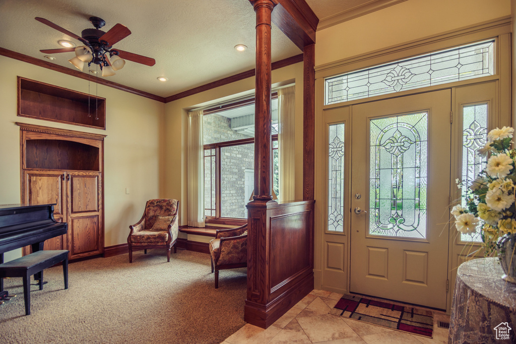 Foyer featuring baseboards, ornamental molding, ceiling fan, and light colored carpet