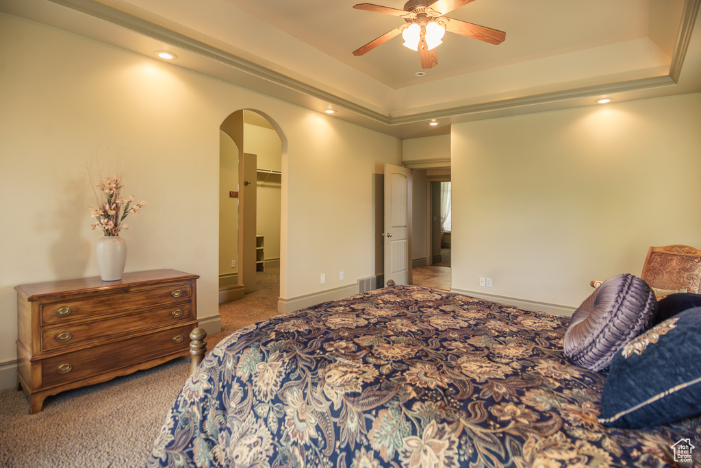Bedroom with arched walkways, a raised ceiling, a spacious closet, carpet, and recessed lighting