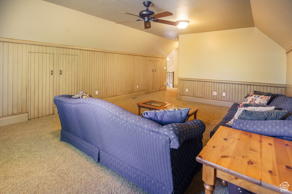 Carpeted home theater room with vaulted ceiling, wainscoting, and a ceiling fan