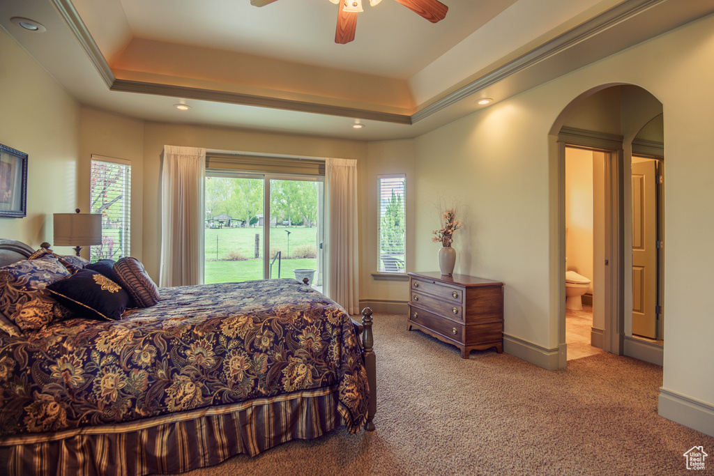 Carpeted bedroom with ceiling fan, access to exterior, arched walkways, a tray ceiling, and recessed lighting