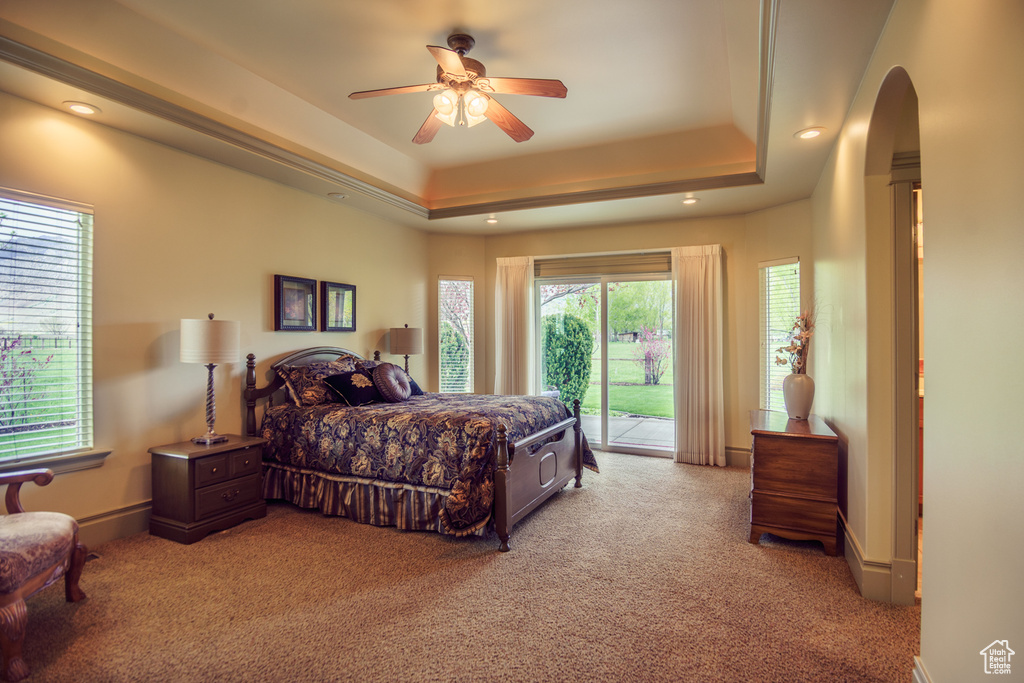 Bedroom featuring access to outside, recessed lighting, a raised ceiling, light colored carpet, and arched walkways