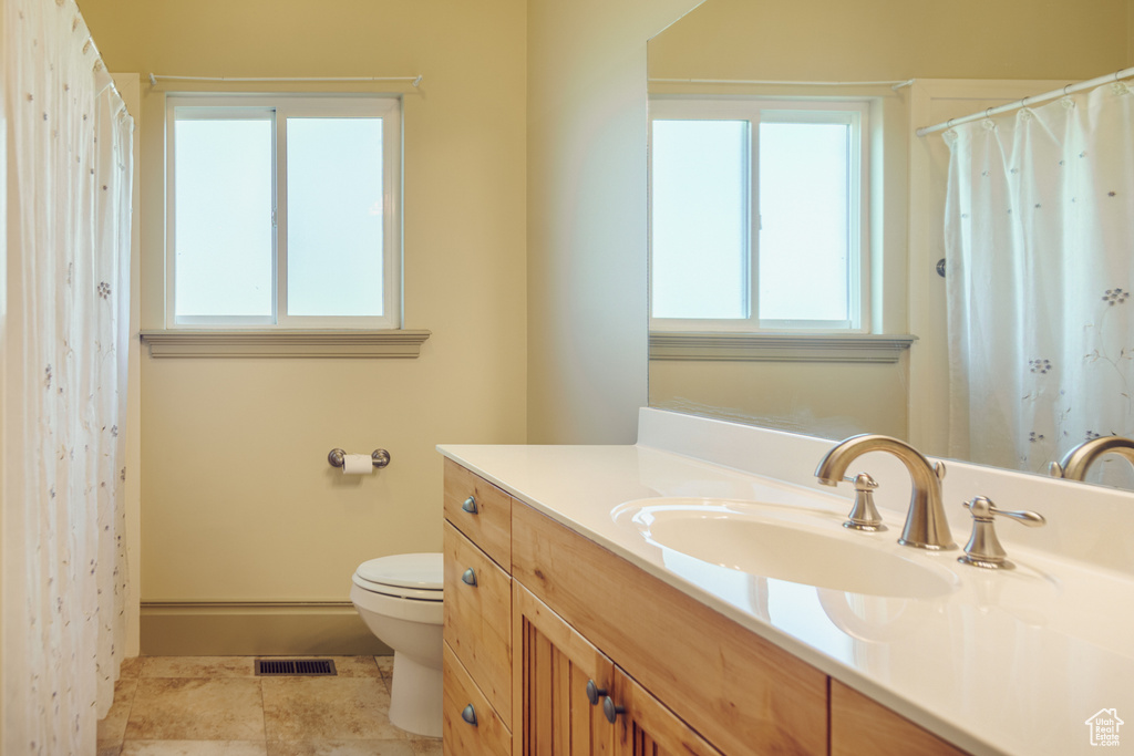 Full bath with visible vents, a wealth of natural light, toilet, and vanity