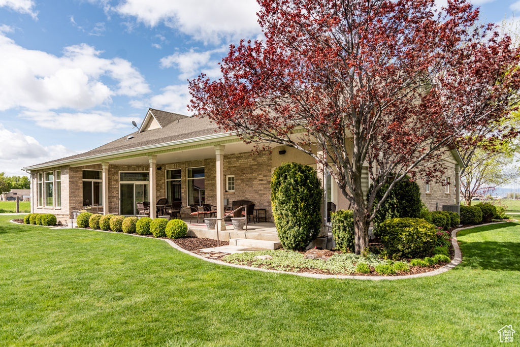 Back of house with a lawn, brick siding, and a patio area