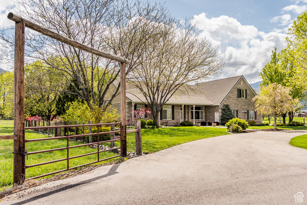 View of front of property featuring curved driveway, a gate, a front yard, and brick siding