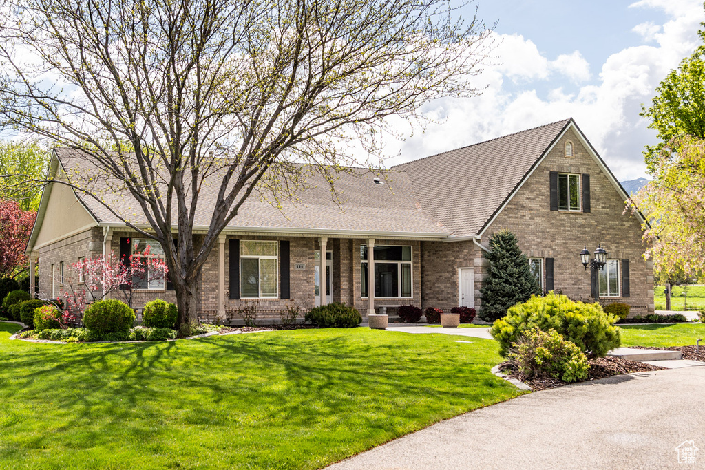 View of front of house featuring a shingled roof, a front lawn, and brick siding