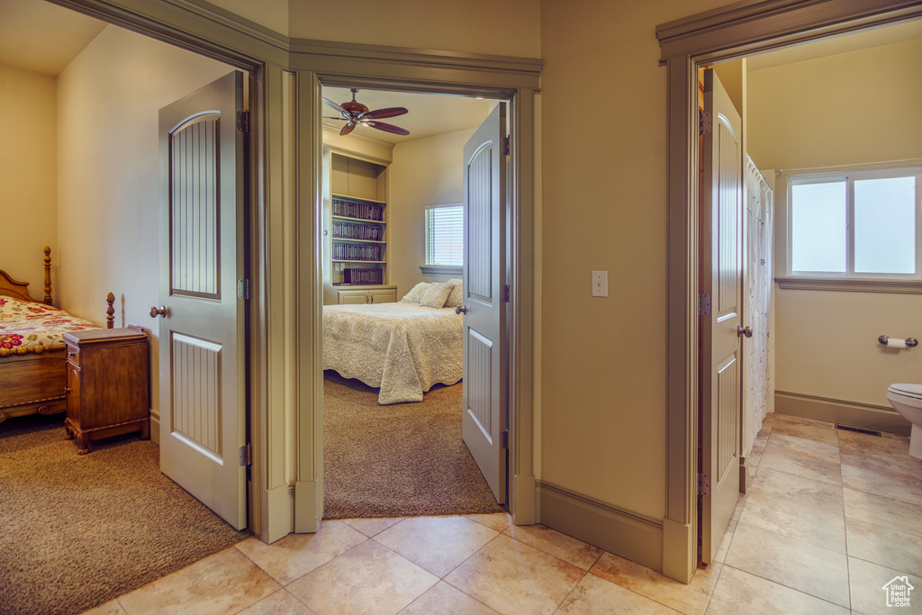Hall with light tile patterned flooring, baseboards, light carpet, and a wealth of natural light