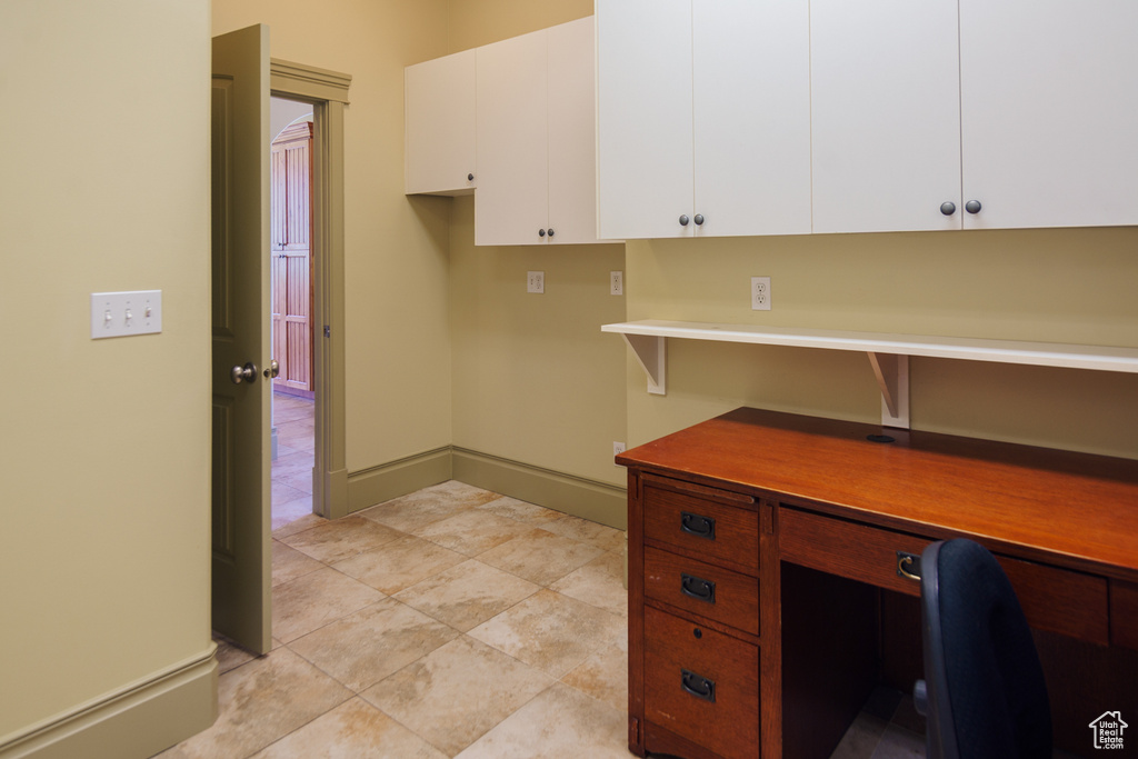 Unfurnished office featuring built in study area and light tile patterned flooring