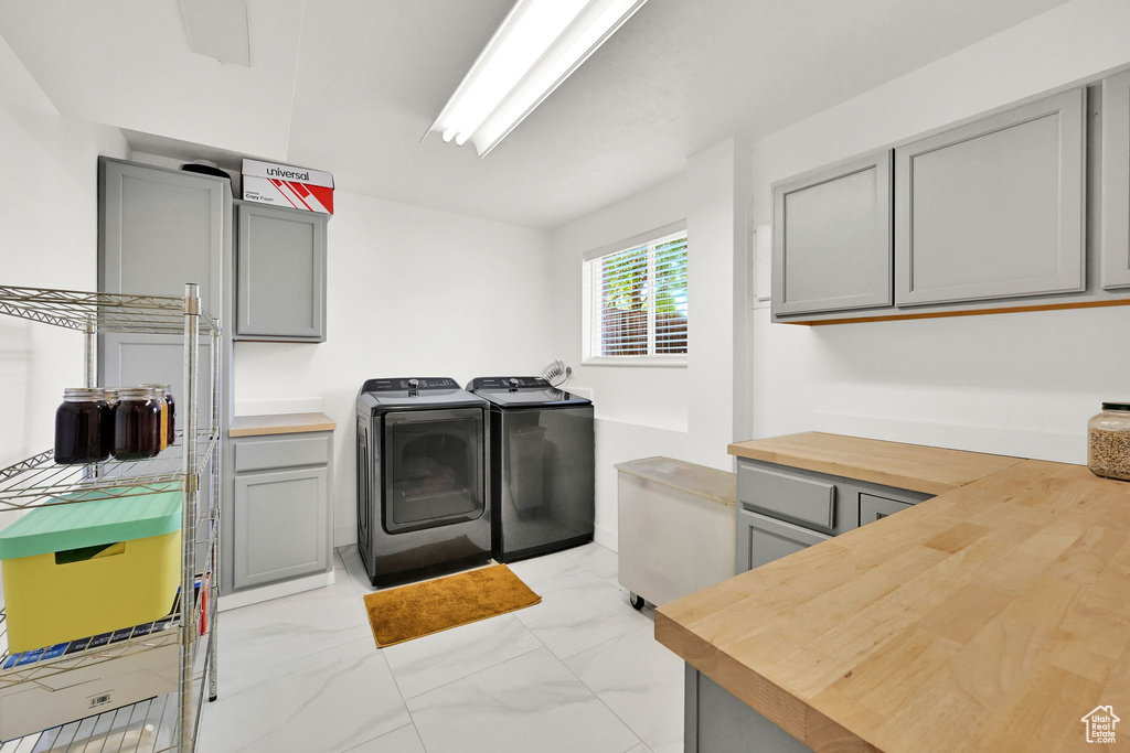 Washroom with marble finish floor, cabinet space, and washing machine and dryer