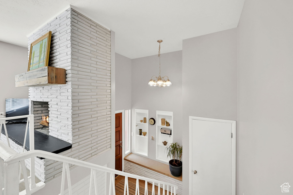 Interior space featuring a fireplace, a chandelier, wood finished floors, and a towering ceiling