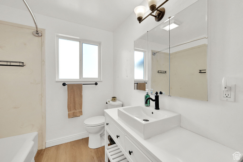 Full bath with wood finished floors, baseboards, vanity, toilet, and washtub / shower combination
