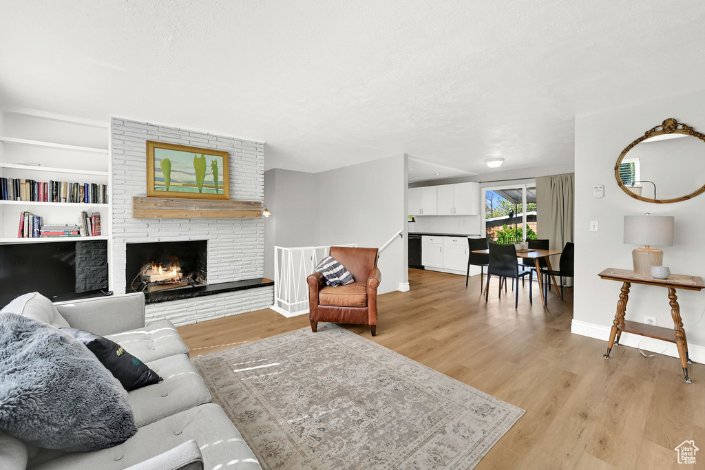 Living room featuring baseboards, light wood-style flooring, and a fireplace