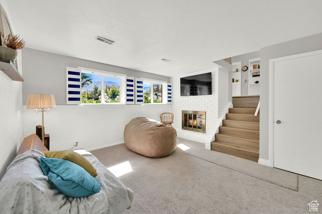 Living area with visible vents, a brick fireplace, carpet floors, and baseboards