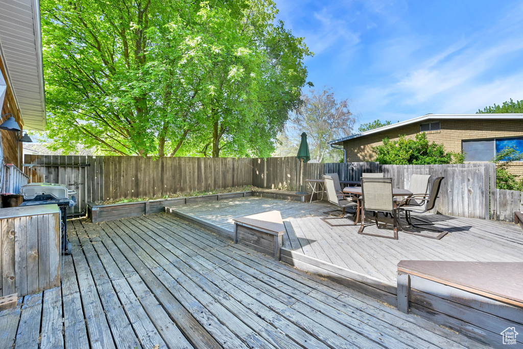 Wooden deck with outdoor dining area and a fenced backyard
