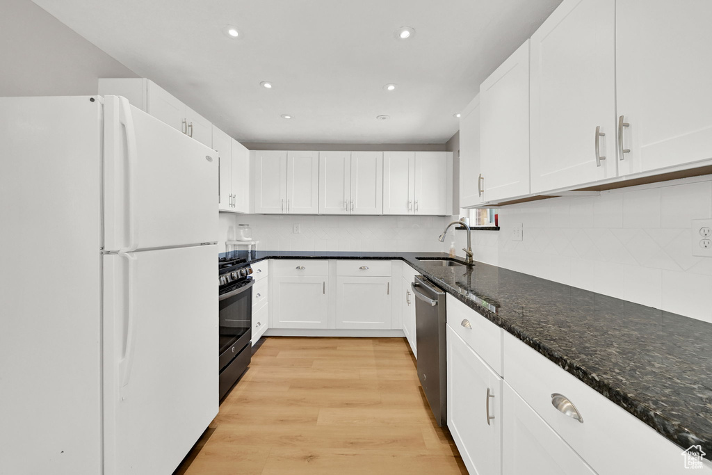 Kitchen with freestanding refrigerator, recessed lighting, range with gas stovetop, and a sink