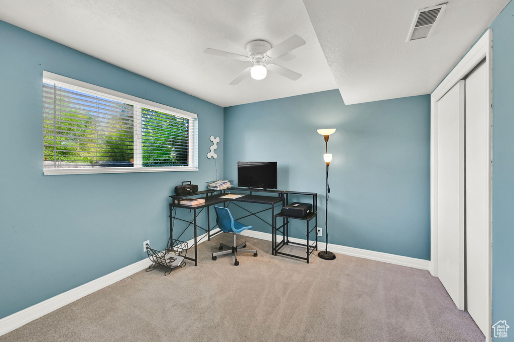 Office space featuring carpet floors, ceiling fan, visible vents, and baseboards