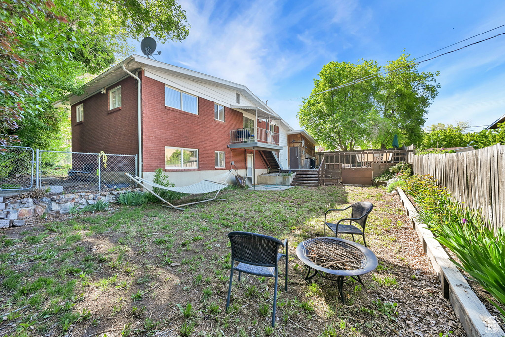 Rear view of house with brick siding, a fire pit, and a fenced backyard