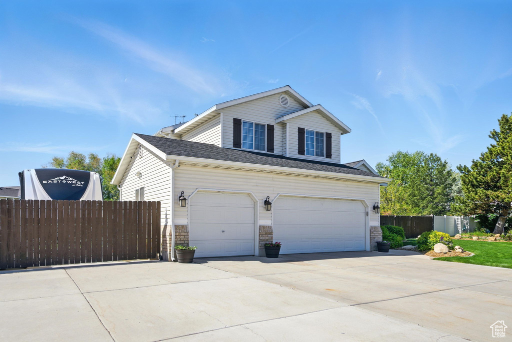 View of front of home with a garage, fence, driveway, and stone siding