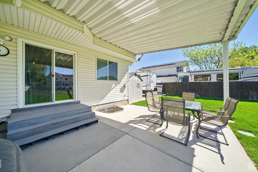 View of patio featuring outdoor dining area, fence, and entry steps
