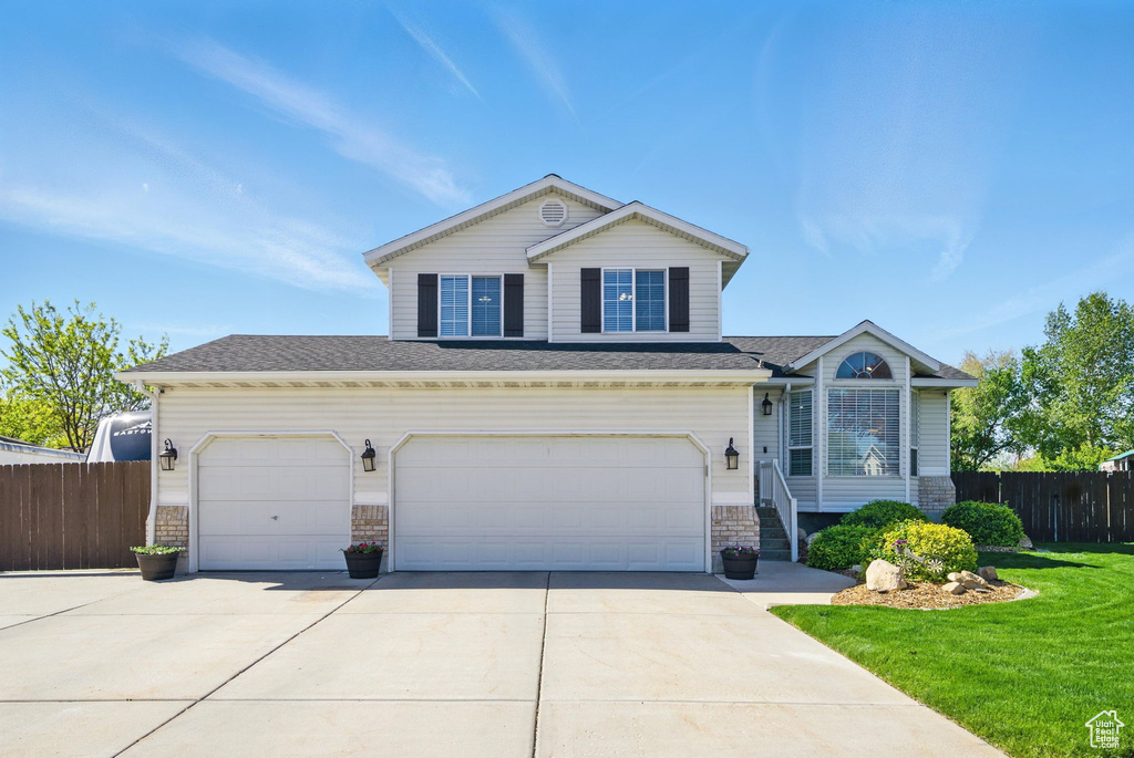 Traditional-style house featuring concrete driveway, fence, and a front yard
