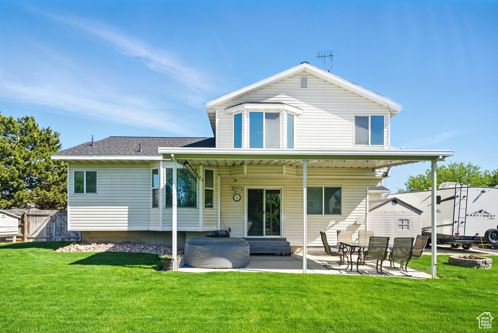 Rear view of house featuring a patio, a lawn, fence, and entry steps