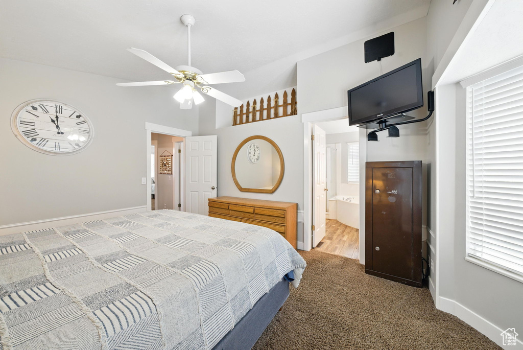 Carpeted bedroom with baseboards, a ceiling fan, ensuite bath, and vaulted ceiling